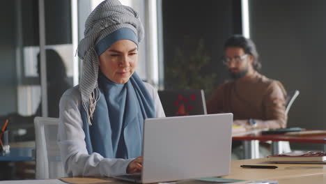 Mujer-Joven-En-Hiyab-Trabajando-En-Una-Laptop-En-La-Oficina